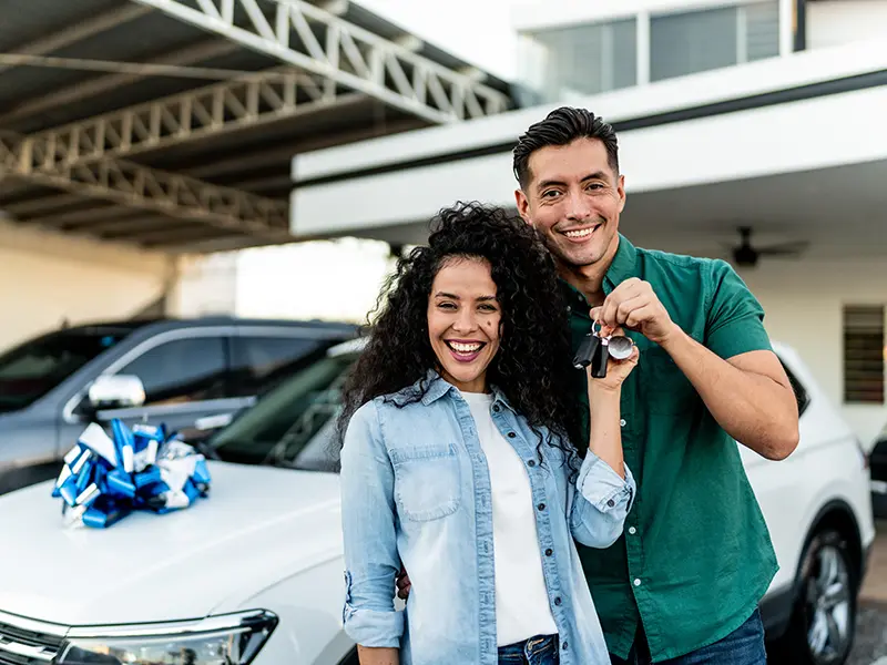 smiling couple in front of new car