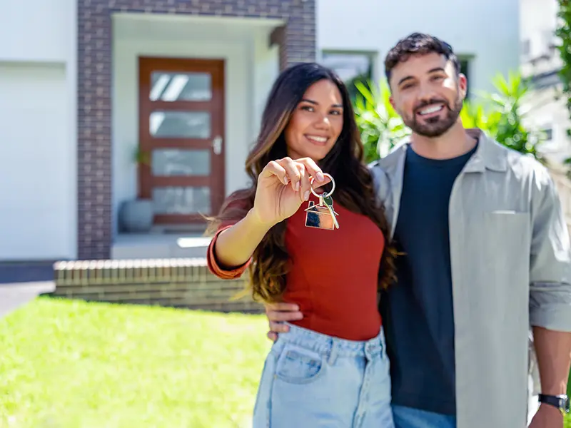couple in front of new home holding key